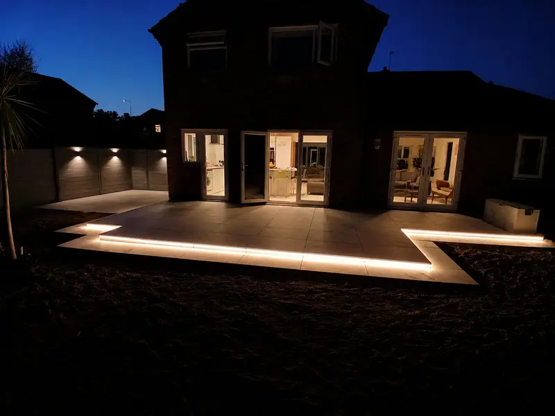 Completed garden transformation at night with two-tone porcelain patio and recessed LED strip lighting