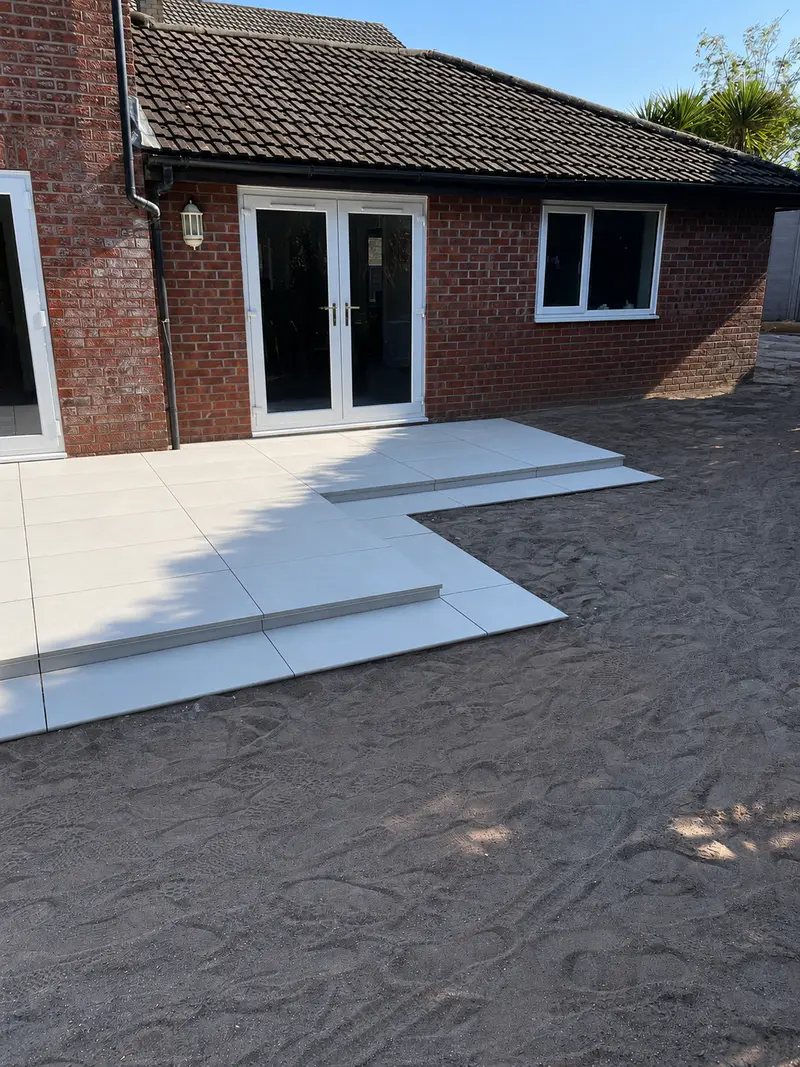 The same garden after the work: new large-format porcelain patio with steps